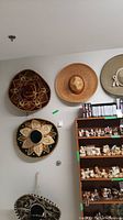 Five sombreros hanging on wall and displayed in room, showing variety of colors and embroidered designs