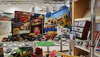 Photo showing multiple boxed and loose miniature Hot Wheels vehicles displayed on metal shelving and yellow plastic car racks.