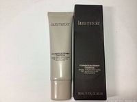 Front view of the Laura Mercier Foundation Primer Radiance tube next to the black packaging box.