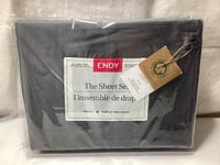 Front view of the folded sheet set in original packaging showing Endy brand label, Twin XL size indication, and tags mentioning 100% organic cotton and eco-certification.