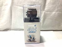 Safari 3 4K 30fps WiFi action camera in clear waterproof housing on top of retail box.