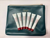 Photo showing six white tubes of Shiseido Ultimune serum arranged on a dark green Shiseido pouch.
