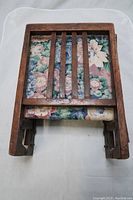 Folded chair showing floral fabric and wooden frame