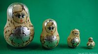 All four miniature Babushka dolls arranged in descending size order on green background.