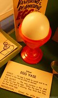 Photo of white egg in red egg vase with box showing 'The Wonderful Vanishing & Reappearing Egg' labeling and description of the egg trick