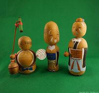 Front view of three Asian wood carved miniature figures showing hand painted details and expressions.