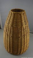 Full side view of wicker lamp shade showing tapered shape and woven wicker material in light brown color.