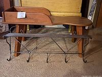 Iron hanging coat rack with multiple hooks and top shelf, placed in front of the bench.