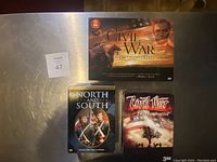 Photo of three Civil War DVD box sets - 'The Civil War 150th Anniversary' (10 DVDs), 'North and South', and 'Civil War Battlefields' (3 DVDs) on a metal surface.