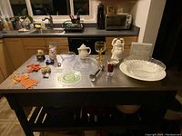 Full overview of all items on metal table including glassware, ceramics, figurines, toys, and decor pieces