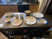 Overview of all serving pieces arranged on a table showing plates, mugs, divided dishes, and serving trays