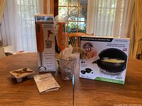 Photo showing Cuisinart hand blender and Cook & Strain pasta pot boxes on table with blender and accessories in front