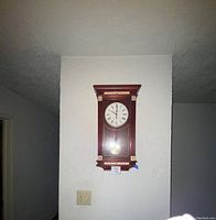 Full view of the vintage Seth Thomas wooden wall clock hanging on a white textured wall showing the overall design.