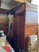 Side view of the solid wood stand-alone closet showing the finish and size, with cardboard boxes around it.