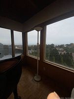 Tall white floor lamp near large windows, showing overall height and structure