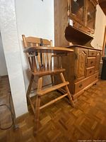 Front angle of solid wood high chair with curved removable tray and spindle backrest, showing turned legs and footrest.