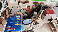Photo of assorted auto accessories including a black handheld vacuum, a hammer with a wooden handle, and other tools alongside the power and air station packaging.