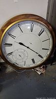 Full view of the 48 inch diameter round wall clock with Roman numerals and wooden frame.