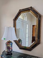 Elongated octagonal wall mirror mounted above a table, showing frame detail and reflection of room.