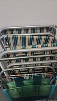 Four lawn chairs stacked showing metal tubular frames and fabric/webbing seating.