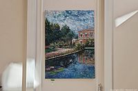 View of framed oil painting hung above fireplace mantel showing villa and reflecting pool scene with detailed brushwork.