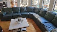 Full view of the leather sectional showing two connected sections forming an L shape around a coffee table.