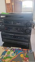 Photo of the front of the GPX stereo system showing various components including radio tuner, equalizer, cassette decks, and phonograph turntable on top.
