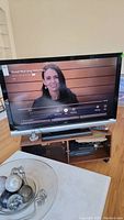 TV displaying a news program, showing the full screen and TV stand below