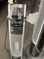 Close-up of silver tower fan showing metal grille and cord.