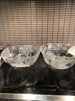 Two large clear glass bowls side by side, showing scalloped edges and floral etched patterns.