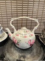 Front view of white ceramic Arthur Wood teapot with pink rose floral pattern and large uniquely curved handle and spout.