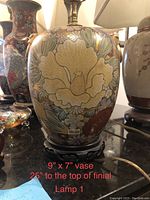 Front view of the hand painted ceramic vase lamp showing large beige flower and surrounding floral details.