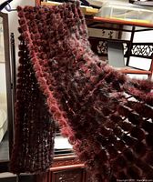 Front view of the knitted mink shawl hanging, showcasing its length, texture, and reddish-brown fur detail.