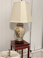 Full view of the vintage handmade Chinese ceramic vase lamp with shade on a wooden stand.