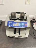 Front view of ARS PRO-NSFCA money counting machine on dark floor with digital display and keypad visible