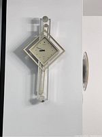 Full view of the modern geometric Seiko wall clock with a tilted square face mounted vertically on a white wall.
