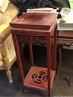 Side view of the solid rosewood plant stand showing carved legs and lattice lower shelf.