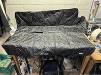 Black quilted BabyLtrl dog/pet vehicle seat cover laid out flat showing full size and shape with back portion extended upward to cover vehicle seat back