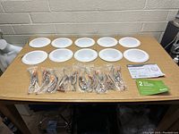 Photo showing 10 white circular Sundo Disk 15W LED downlights laid out on a table, wired connectors in plastic bags in front, with warranty pamphlet visible
