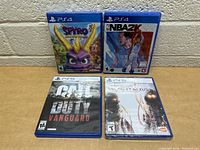 Photo showing four video game cases including Spyro Reignited Trilogy and NBA 2K22 for PS4; Call of Duty Vanguard and Scarlet Nexus for PS5.