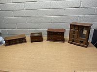 Four wooden jewelry boxes displayed on a table, showing varying sizes and drawer configurations.