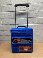 Blue Hot Wheels 100 Car Suitcase with attached diecast car and extendable handle.