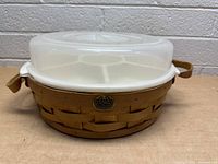 Front view of vintage Peterboro woven basket showing leather handles and metal label with plastic divided lid on top.