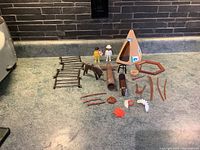 Full layout of the 1974 Geobra Indian Set including figures, horse, canoe, fencing, totem pole, campfire pieces, and weapons all displayed together on a countertop.
