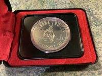 Front view of the 1975 Canadian Calgary Centennial silver dollar coin in black protective holder with red velvet-lined box.