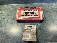 Photo showing the red and white worn box containing six classic diecast metal cars and a Diet Pepsi metal keychain in small blister package