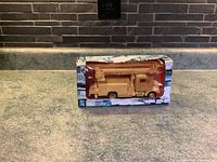 Image showing front-left side of beige Peterbilt Model 335 toy truck in open box with worn packaging.
