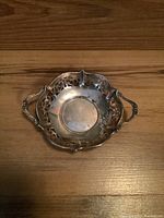Front angle view of sterling silver candy dish showing its overall shape, handles, and pierced decorative edge.