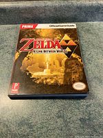 Front cover of The Legend of Zelda: A Link Between Worlds Official Game Guide by Prima, showing the title and artwork with some wear on the cover.