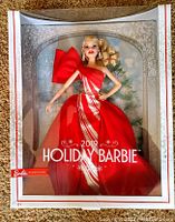 Front view of the Barbie doll in box showing the doll dressed in bright red holiday gown with silver stripes and big red bow on shoulder.